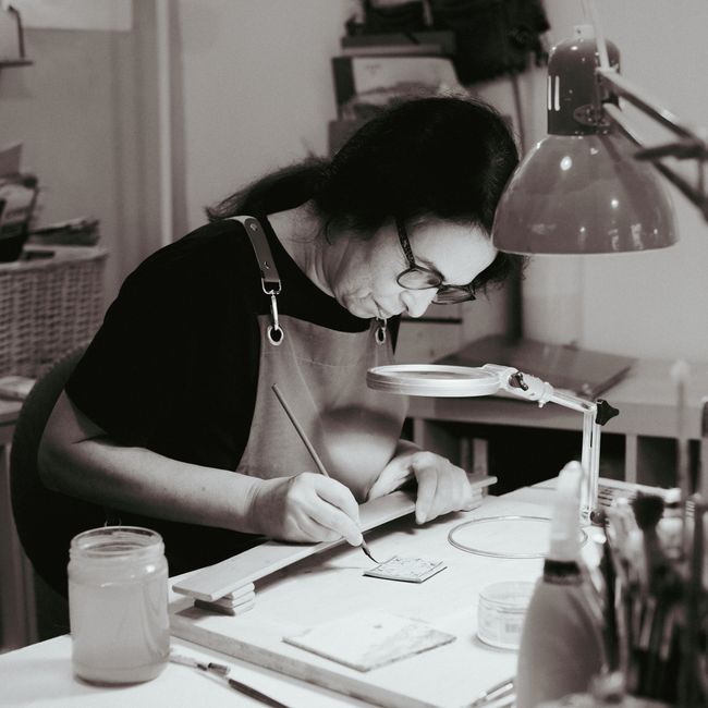 A talented artisan engrossed in ceramic painting at a Lisbon studio, showcasing traditional craftsmanship.